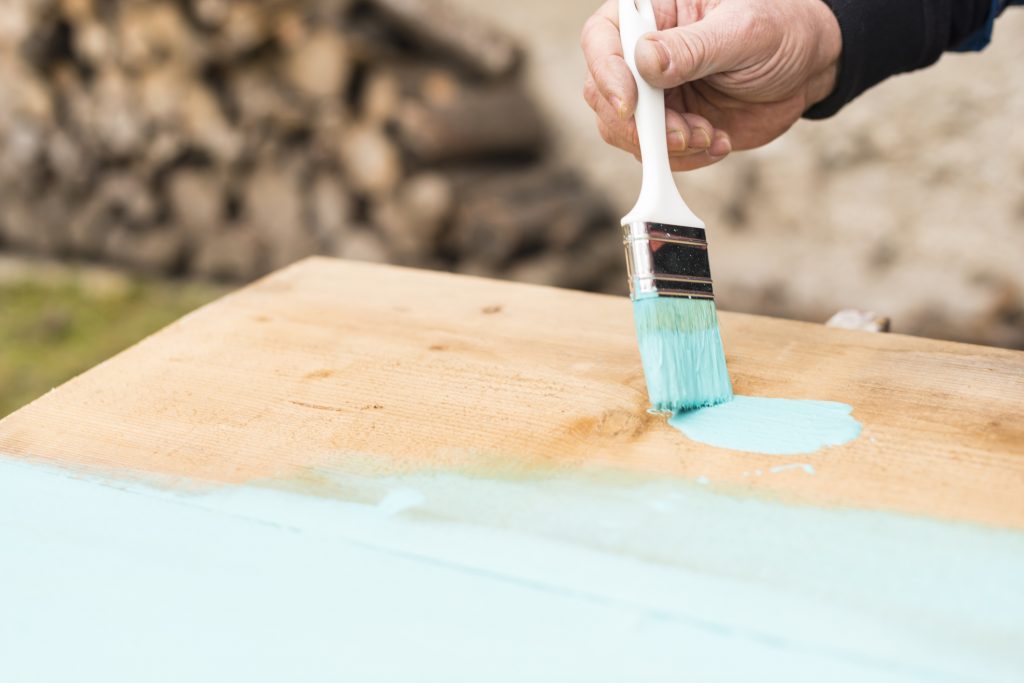 Painting a wooden plank using paintbrush